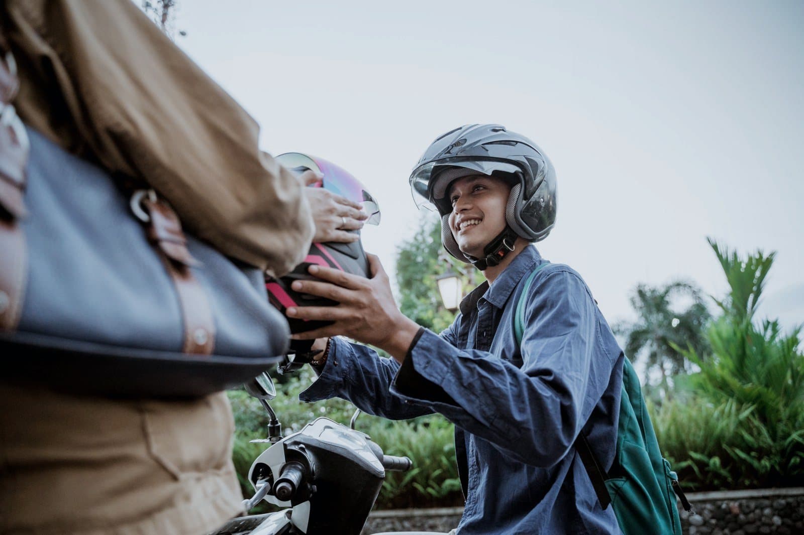 Mototaxista entregando o capacete ao passageiro